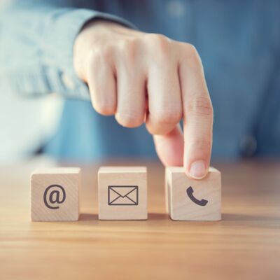 Holzwürfel mit Icons zur Kontaktaufnahme und Hand an einem Würfel/GO Europe