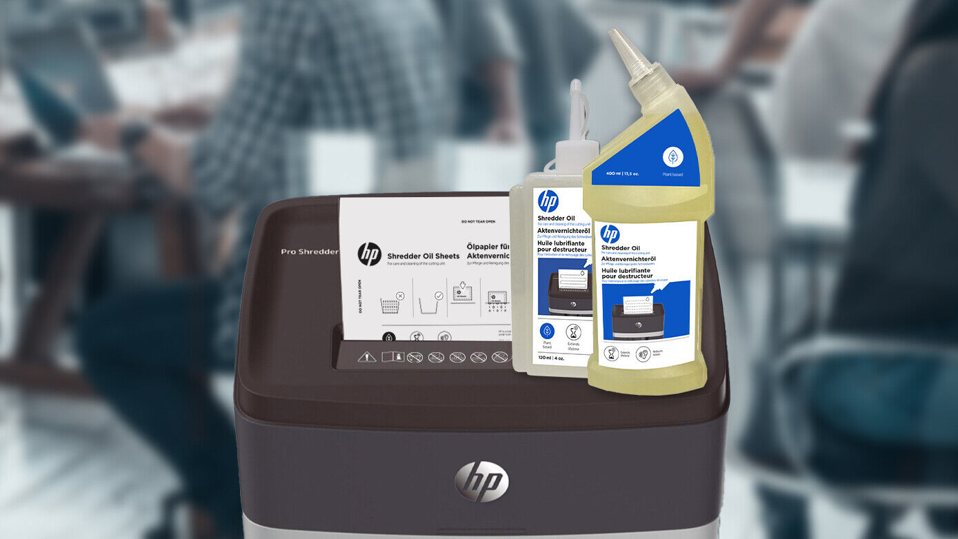 Huile de 120 ml et bouteille de 400 ml sur la déchiqueteuse HP Pro Shredder avec papier huilé et bureau ouvert en arrière-plan/GO Europe