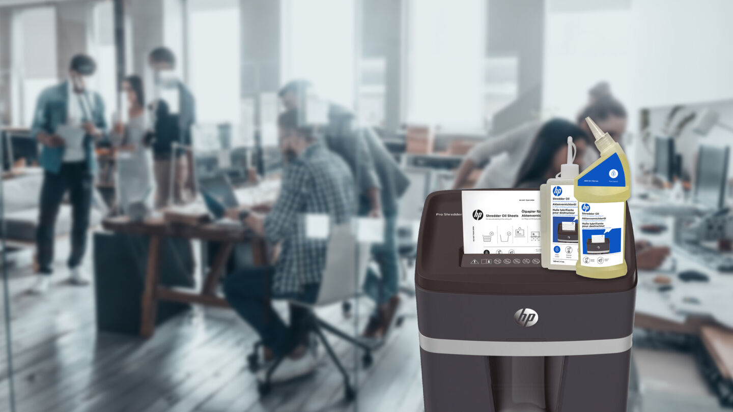 Huile de 120 ml et bouteille de 400 ml sur la déchiqueteuse HP Pro Shredder avec papier huilé et bureau ouvert en arrière-plan/GO Europe